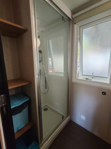 La salle de bains est pourvue d'une douche et d'une fenêtre. dans l'établissement Mobil home 6 personnes, à Sainte-Croix-de-Verdon