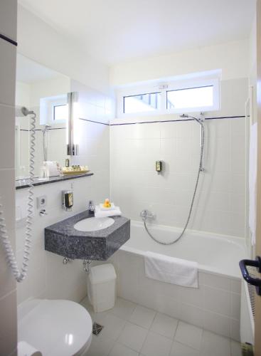 a white bathroom with a sink and a shower at Best Western Plus Hotel Steinsgarten in Gießen