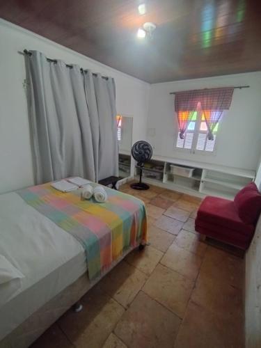 a bedroom with a bed and a chair and windows at Solar dos Ventos BANANEIRAS in Bananeiras