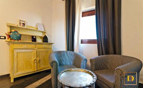 a living room with two chairs and a cabinet at Dammusi Ambra in Pantelleria