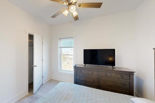 a bedroom with a ceiling fan and a television on a dresser at Seabreeze Shores 3 in Rodanthe