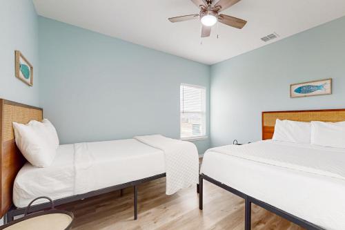 two beds in a room with a ceiling fan at Red Fish, Blue Fish in Aransas Pass