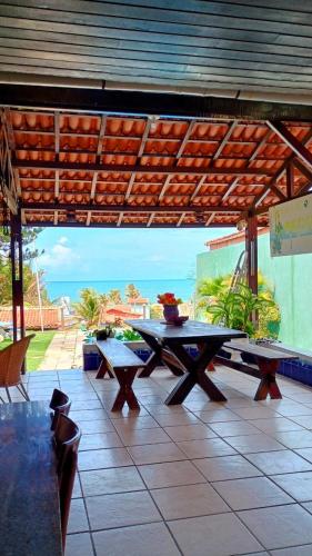 a patio with two picnic tables under a wooden roof at Doce Uruaú in Beberibe