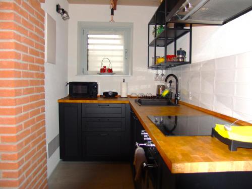 a kitchen with black cabinets and a brick wall at Modern Loft Near Lake Como in Bulciago