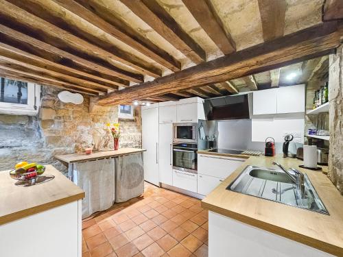a large kitchen with white cabinets and a sink at Ancienne dépendance du Duc de Normandie - Château in Caen