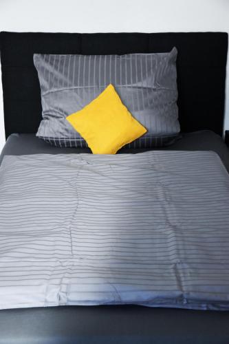 a bed with a yellow pillow and some pillows at Villa C&C in Bad Wildungen