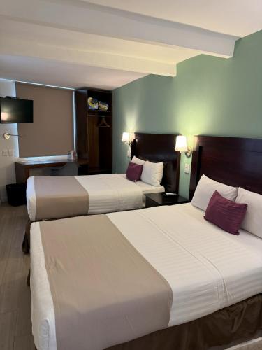 a hotel room with two beds and a desk at Hotel Arribo in Lagos de Moreno