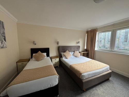 a hotel room with two beds and a window at The Waverley Inn in Dingwall