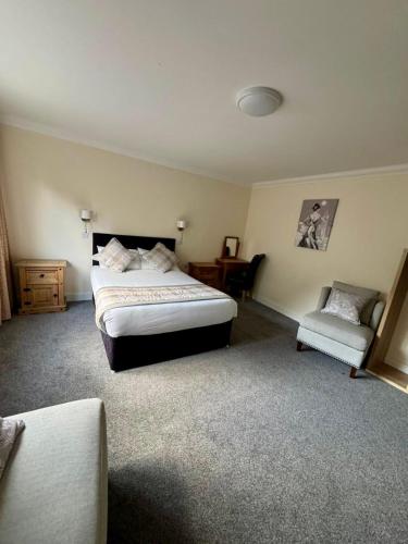 a bedroom with a bed and a chair at The Waverley Inn in Dingwall