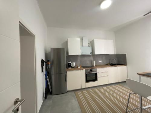 eine Küche mit weißen Schränken und einem Edelstahlkühlschrank in der Unterkunft Danisman Apartments 3 Zentral - Smart - Modern in Saarbrücken