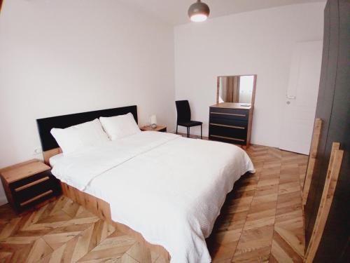 a bedroom with a white bed and a wooden floor at Agoraapartment in Peje