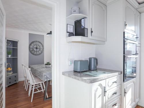 a kitchen and dining room with white cabinets and a table at Glasfryn in Holyhead