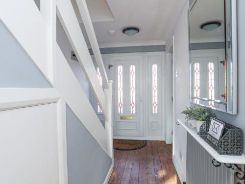 a hallway with white walls and a staircase with windows at Glasfryn in Holyhead