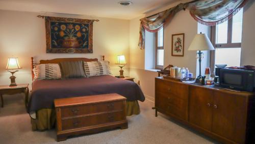 a bedroom with a bed with a dresser and a tv at Mountain Creek Tavern in Mount Holly Springs