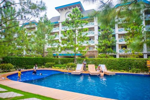 une piscine devant un grand bâtiment dans l'établissement The Zen Den, Pine Suites Tagaytay, à Tagaytay