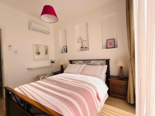 a bedroom with a bed with a pink and white blanket at Seafront holiday home surrounded by nature in Tatlisu, Northern Cyprus in Akanthou