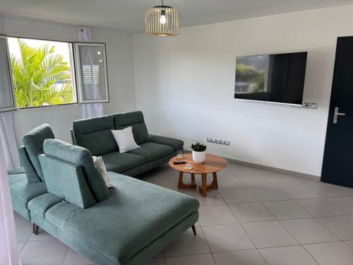 a living room with two green couches and a table at Nomade Evasion - Escale Paisible in Petit-Bourg