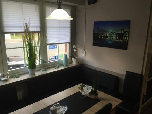 a living room with a table and two windows at Hotel Ammerland garni in Wilhelmshaven
