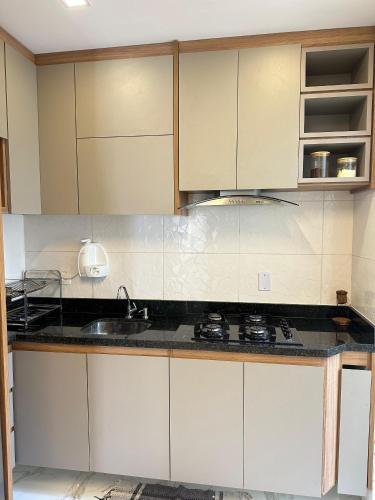 a kitchen with white cabinets and a sink at Casa 03 Suites 100 metros da Praia in Lauro de Freitas