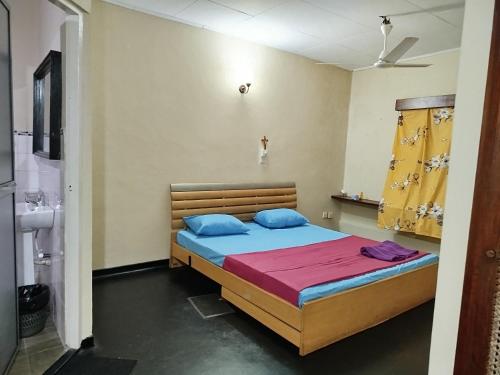 a bedroom with a bed with blue pillows at Holy Spirit Mission Camps in Mount Lavinia