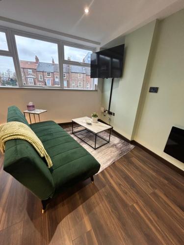 a living room with a green couch and a flat screen tv at NEW! Amazing Studio Apartment Sleeps 3 Hull Central in Hull