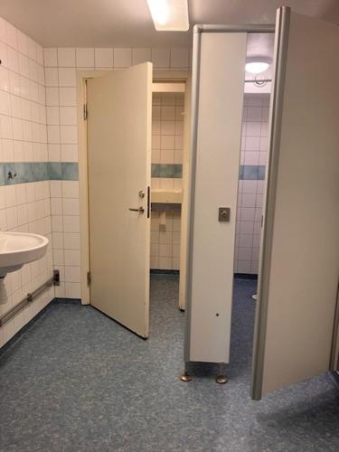 a bathroom with two doors and a sink and a toilet at Bredsands camping och bad Vandrarhem in Enköping