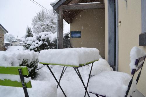 a snow covered bench in front of a house at Gîte La Clef des Champs in Libin