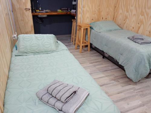 two beds sitting in a room with wooden floors at Dos Charitos in El Chalten