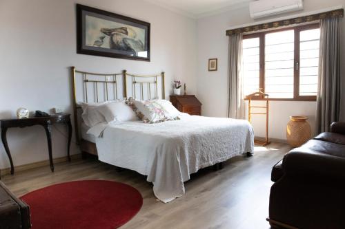 a bedroom with a white bed and a red rug at Hotel Don Alfonso in Pereira
