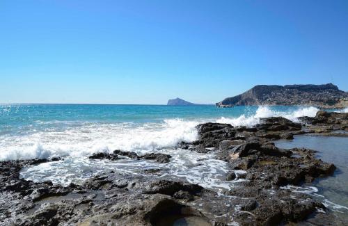 a beach with waves crashing on the rocks at Residencial Terra de Mar Calpe, Grupo Terra de Mar, alojamientos con encanto in Calpe