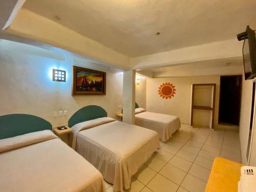 a hotel room with two beds and a tv at Hotel Real Monrey in Zihuatanejo
