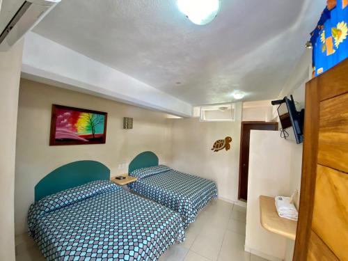 a bedroom with two beds and a tv on the wall at Hotel Real Monrey in Zihuatanejo