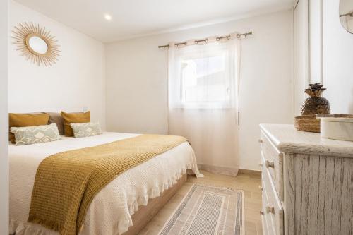 a white bedroom with a bed and a window at CASA Castelejo in Vila do Bispo