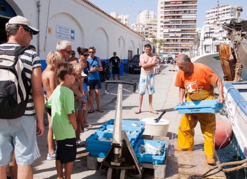 a group of people standing around a man working on a boat at Residencial Terra de Mar Calpe, Grupo Terra de Mar, alojamientos con encanto in Calpe