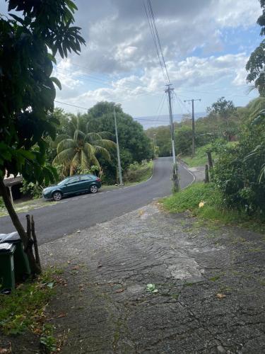 a green car is driving down a road at Chez nana in Pointe-Noire