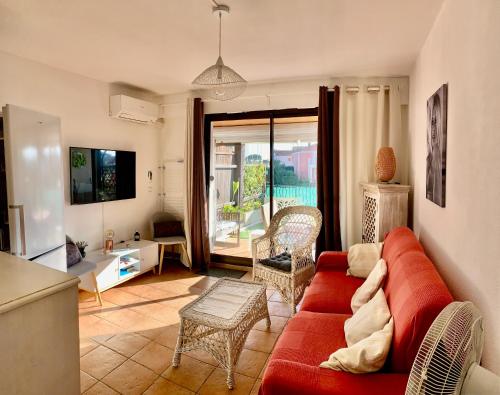 un salon avec un canapé rouge et une table dans l'établissement Appartement rue de l'amarrage à PORT GRIMAUD avec Terrasse vue canaux et garage, à Grimaud