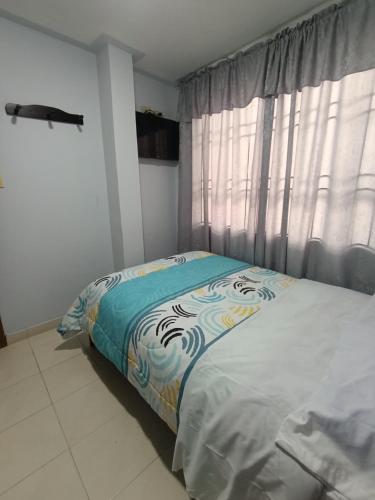 a bedroom with a bed and a window with curtains at Hotel Gamma Pasto in Pasto