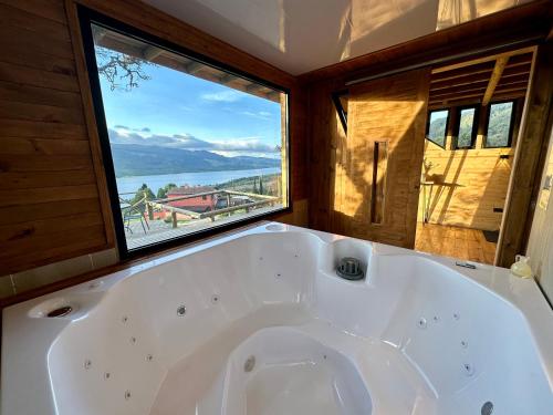 a large white tub in a room with a large window at Neusa Hills Glamping in Tausa Viejo
