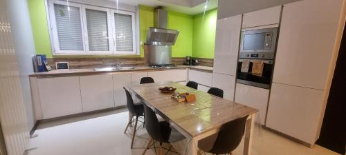 d'une cuisine avec une table en bois et des murs verts. dans l'établissement Le Torii - Les gîtes d'Hélène et Wil, à Maurepas