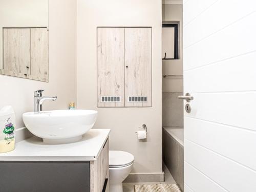 a white bathroom with a sink and a toilet at Binbin Serenity Suite in Midrand