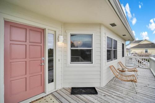 a house with a red door and two chairs on a porch at Charming Newly Renovated 3-Bedroom Home on Nautical Watch in Nautical Watch Villas