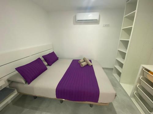 a bed with purple pillows and a teddy bear on it at Alaram Holidays House in Arguineguín