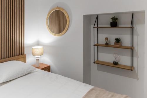 a bedroom with a white bed and a mirror at Résidence Serbie - Appartements design et climatisés en centre ville in Vichy