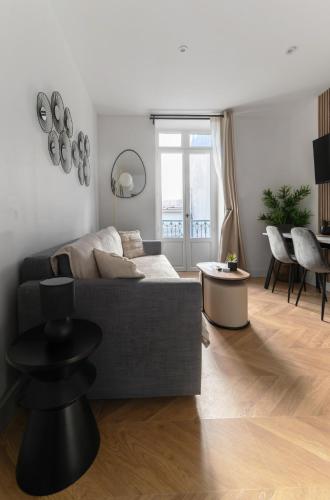 a living room with a gray couch and a table at Résidence Serbie - Appartements design et climatisés en centre ville in Vichy