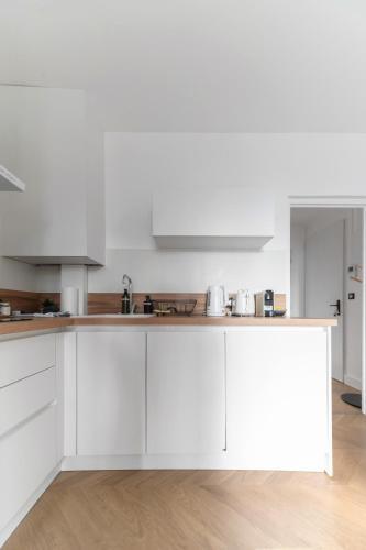 a white kitchen with white cabinets and a counter at Résidence Serbie - Appartements design et climatisés en centre ville in Vichy