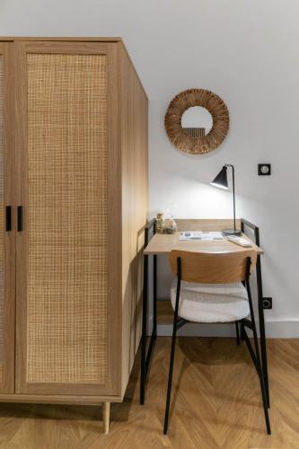 a desk with a chair next to a wooden cabinet at Résidence Serbie - Appartements design et climatisés en centre ville in Vichy