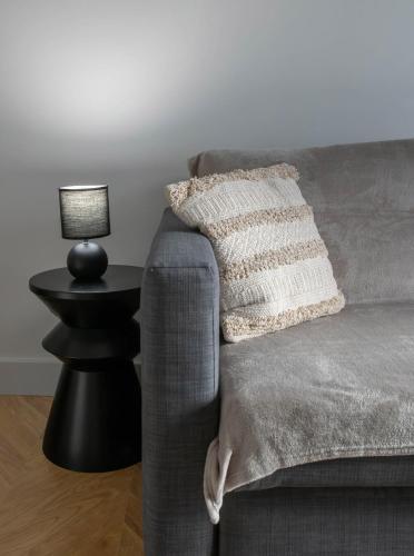 a couch with a pillow and a lamp on a side table at Résidence Serbie - Appartements design et climatisés en centre ville in Vichy