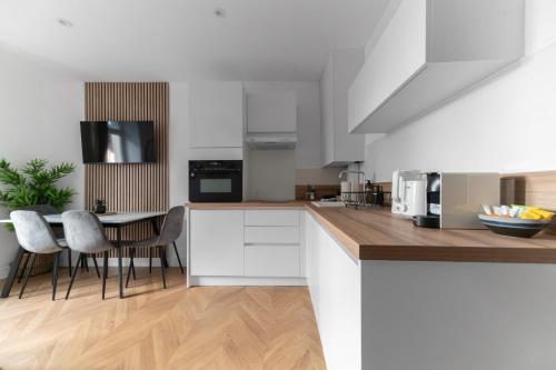 a kitchen with white cabinets and a table with chairs at Résidence Serbie - Appartements design et climatisés en centre ville in Vichy