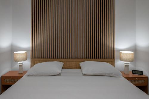a white bed with two nightstands and two lamps at Résidence Serbie - Appartements design et climatisés en centre ville in Vichy