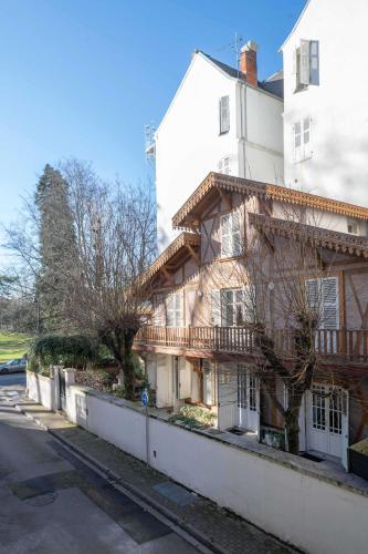 an old wooden house next to a white building at Résidence Serbie - Appartements design et climatisés en centre ville in Vichy